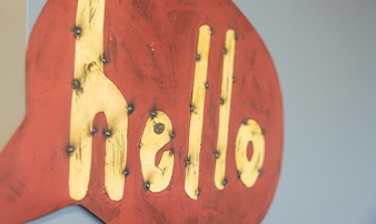 Sign on wall with red speech bubble and yellow letters saying hello
