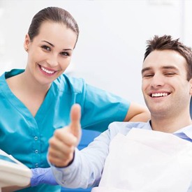 Smiling man in dental chair giving thumbs up