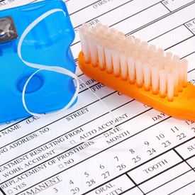 Toothbrush and floss on dental insurance form