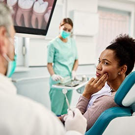 Woman with toothache talking to dentist during exam