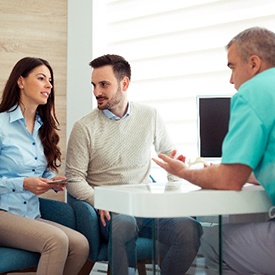 Couple sitting in dentist's office while discussing cost of veneers