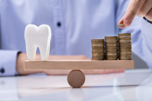 Man Stacking Coins Over Seesaw with Balancing Tooth