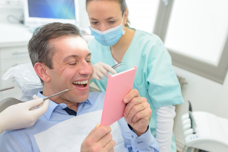 Man looking at his teeth after direct bonding